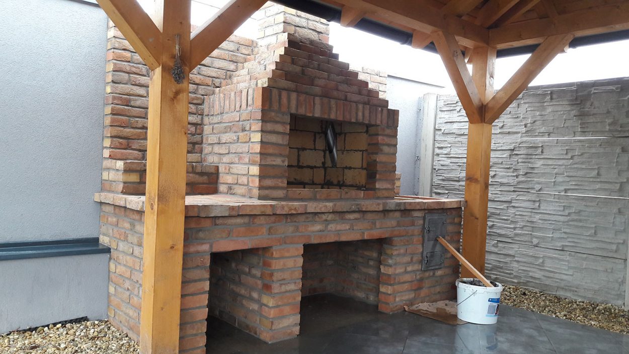 Vonkajší krb a gril z ručne pálenej tehly pod dreveným prístreškom